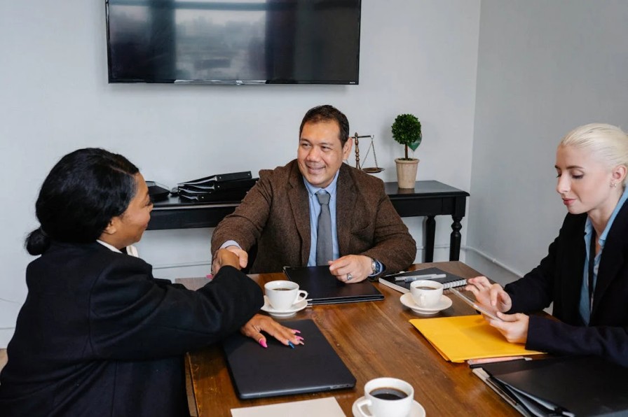 A child custody lawyer shaking hands with his client with a justice scale at the back