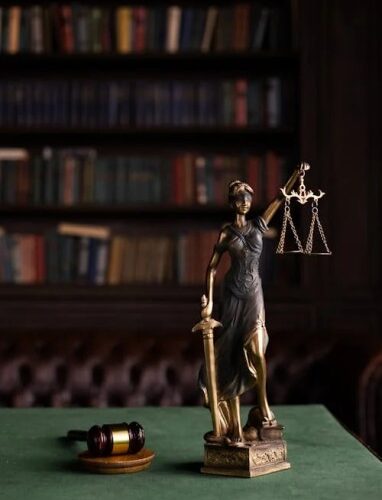 A Lady of Justice statue and a wooden gavel on a table